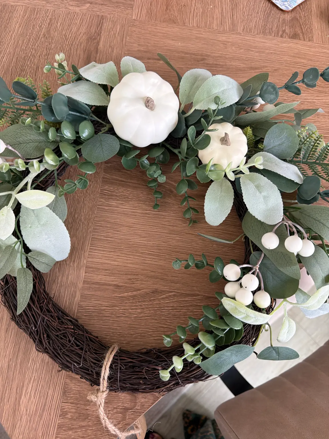 A simple wreath of sage and cream leaves, berries and two white pumpkins on a twig base